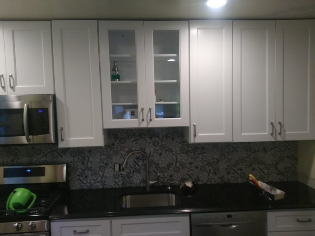 White shaker kitchen cabinets with granite countertops and stainless appliances in a Maryland remodel