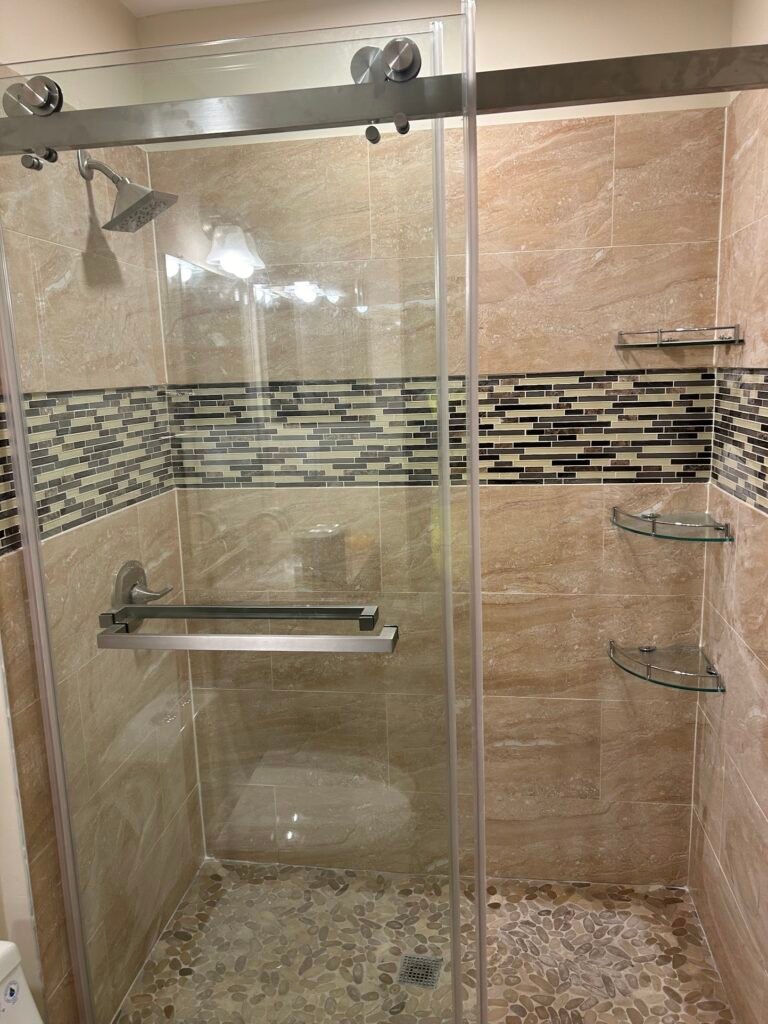 Custom tiled shower with sliding glass doors and decorative tile band